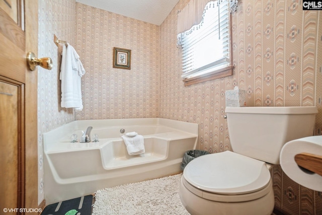 bathroom with a textured ceiling, a bathtub, and toilet