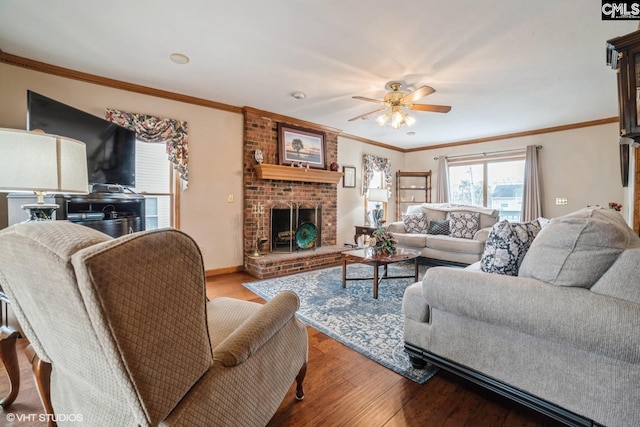 living room with crown molding, ceiling fan, wood-type flooring, and a brick fireplace