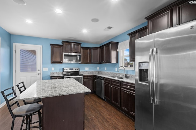 kitchen featuring a kitchen breakfast bar, dark hardwood / wood-style flooring, sink, appliances with stainless steel finishes, and a center island