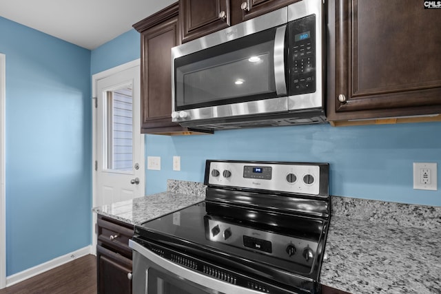 kitchen with light stone counters, dark wood-type flooring, dark brown cabinetry, and stainless steel appliances