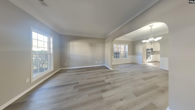 interior space featuring an inviting chandelier, light hardwood / wood-style flooring, a wealth of natural light, and ornamental molding