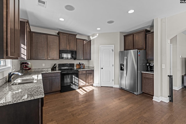 kitchen with sink, dark brown cabinets, dark hardwood / wood-style floors, black appliances, and light stone countertops