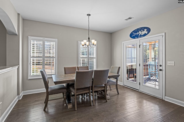 dining area featuring dark wood-type flooring and an inviting chandelier