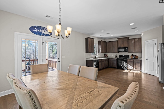 dining area with a healthy amount of sunlight, dark hardwood / wood-style floors, sink, and a notable chandelier