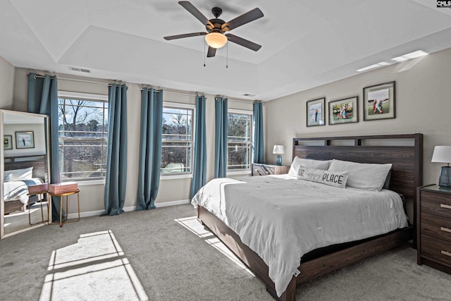 carpeted bedroom with a raised ceiling and ceiling fan