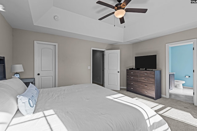 bedroom featuring light carpet, a tray ceiling, and ensuite bath