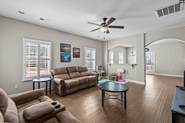 living room with plenty of natural light, ceiling fan with notable chandelier, and dark hardwood / wood-style flooring