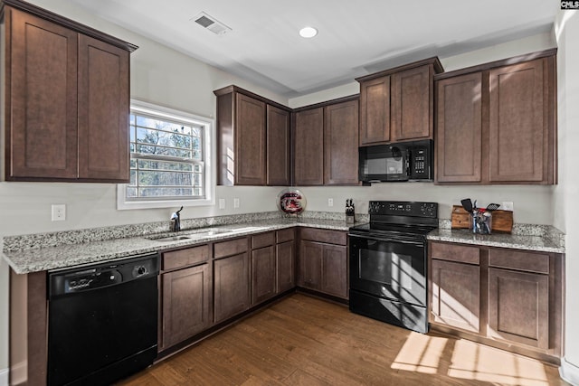 kitchen featuring sink, dark wood-type flooring, dark brown cabinetry, light stone countertops, and black appliances