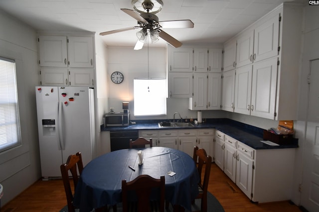 kitchen with a healthy amount of sunlight, sink, white fridge with ice dispenser, and white cabinets