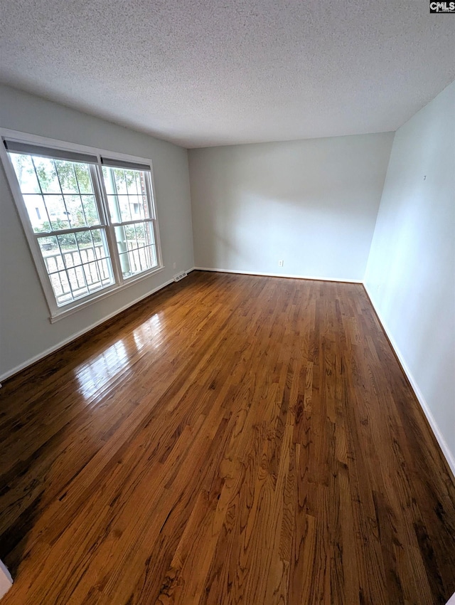 unfurnished room with a textured ceiling and dark hardwood / wood-style floors