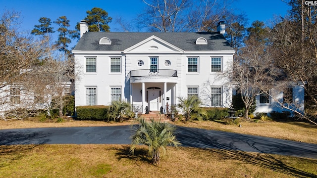 view of front of home with a balcony and a front lawn