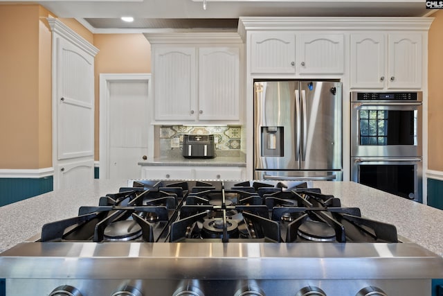 kitchen featuring ornamental molding, backsplash, white cabinetry, and stainless steel appliances