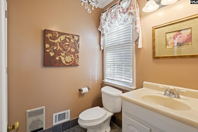 bathroom featuring toilet, heating unit, and vanity