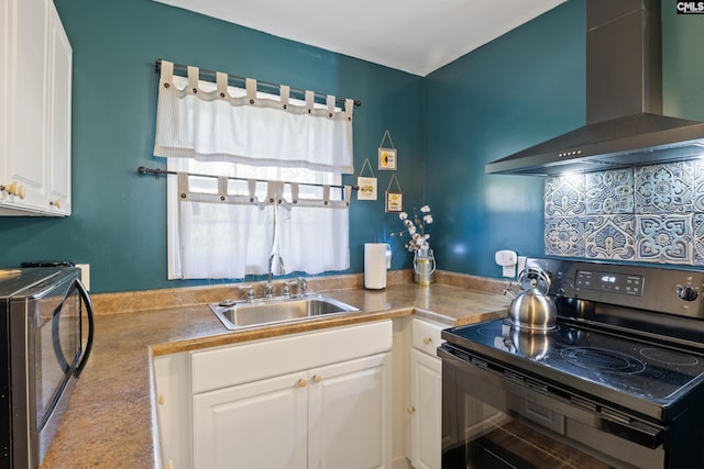 kitchen featuring black electric range oven, wall chimney range hood, white cabinets, and sink