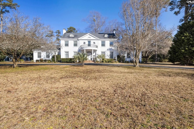 view of front of home with a balcony and a front lawn