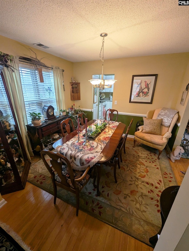 dining area featuring hardwood / wood-style floors, independent washer and dryer, a textured ceiling, and a notable chandelier