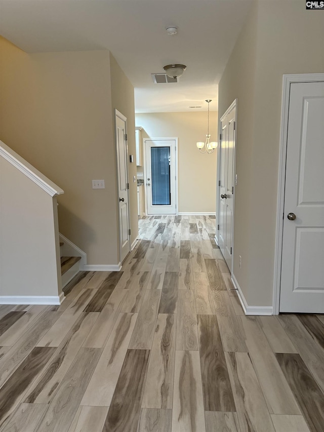 hallway featuring light hardwood / wood-style flooring and a notable chandelier