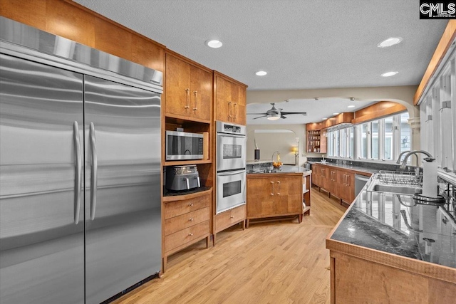 kitchen featuring sink, ceiling fan, stainless steel appliances, light hardwood / wood-style floors, and a textured ceiling