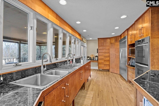 kitchen featuring sink, plenty of natural light, stainless steel appliances, and light wood-type flooring