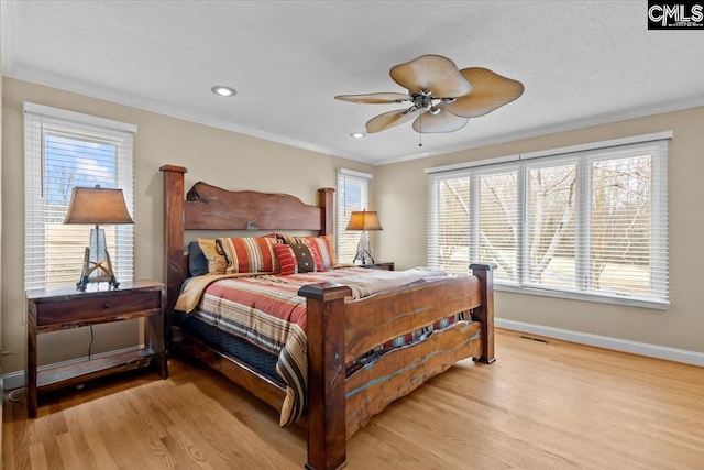 bedroom with multiple windows, ornamental molding, ceiling fan, and light hardwood / wood-style flooring