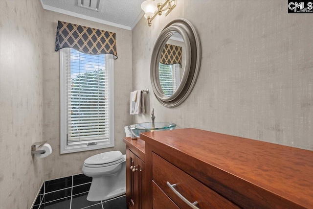 bathroom with toilet, crown molding, a textured ceiling, vanity, and tile patterned flooring