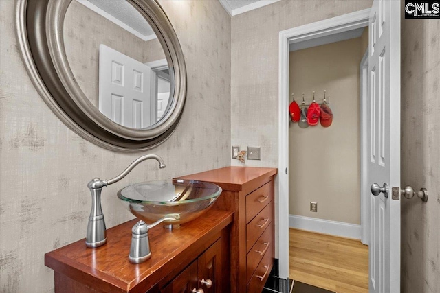 bathroom featuring hardwood / wood-style flooring, ornamental molding, and vanity