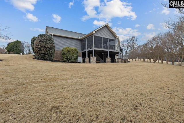 back of property featuring a sunroom and a lawn