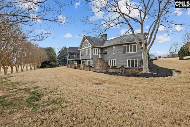 back of property with a sunroom and a lawn