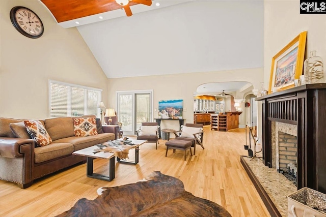 living room featuring ceiling fan, high vaulted ceiling, a fireplace, and light hardwood / wood-style floors