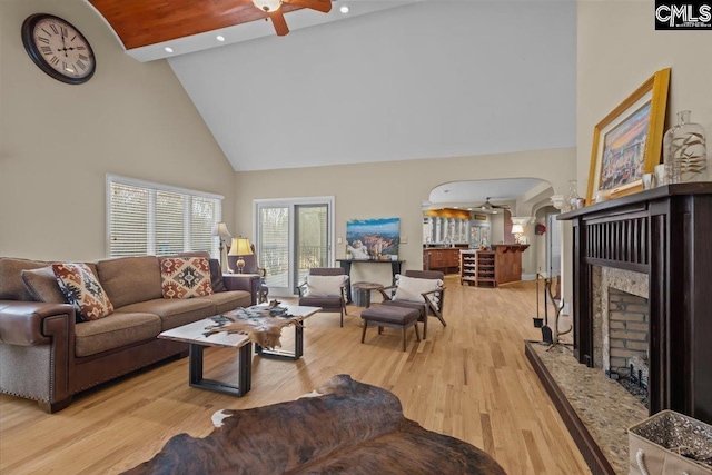 living room featuring ceiling fan, a premium fireplace, high vaulted ceiling, and light hardwood / wood-style flooring