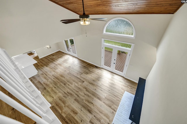 unfurnished living room with wooden ceiling, light wood-type flooring, high vaulted ceiling, and french doors