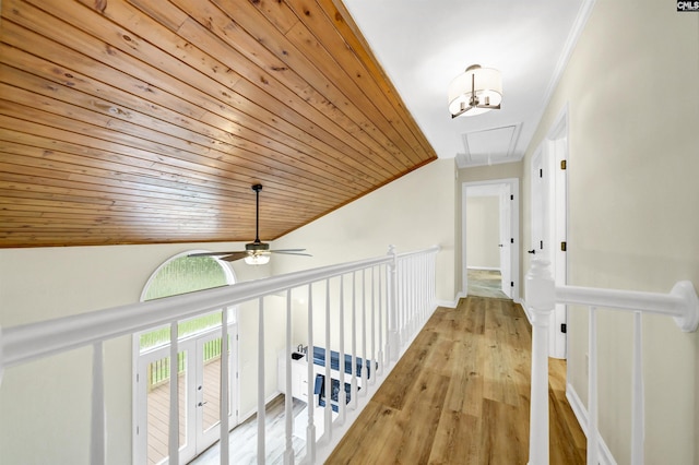 corridor with light wood-type flooring, vaulted ceiling, ornamental molding, and wooden ceiling