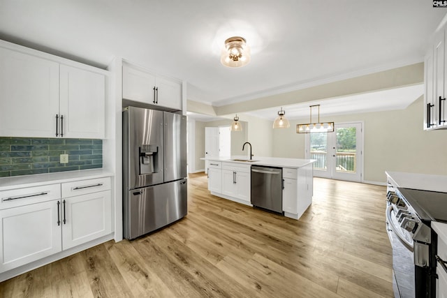 kitchen with appliances with stainless steel finishes, white cabinetry, decorative backsplash, sink, and hanging light fixtures