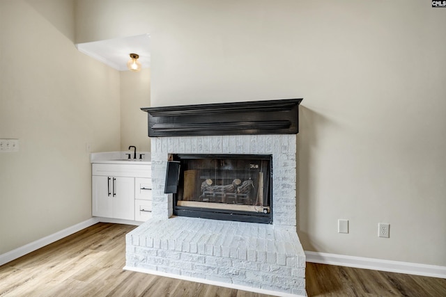 interior details featuring sink, hardwood / wood-style flooring, and a brick fireplace