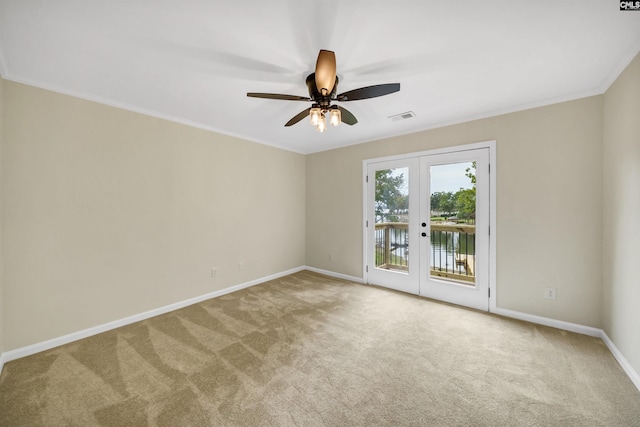 carpeted spare room featuring ceiling fan, crown molding, and french doors