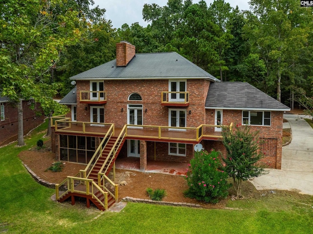 rear view of property featuring a lawn and a wooden deck