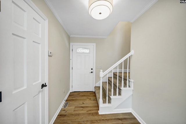 entryway with ornamental molding and wood-type flooring