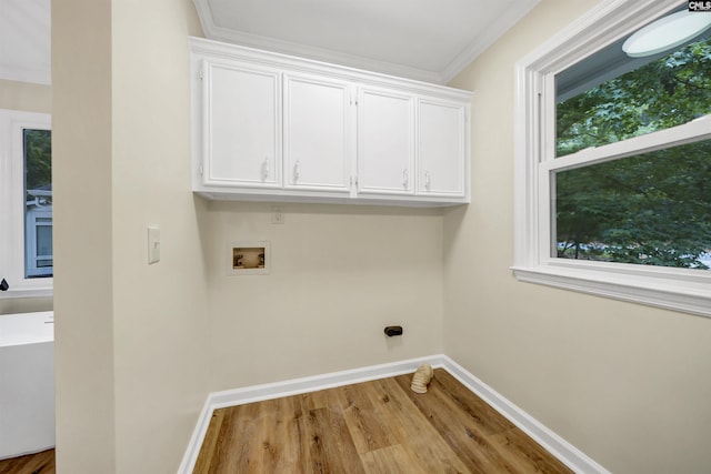 clothes washing area featuring washer hookup, crown molding, light hardwood / wood-style floors, and cabinets