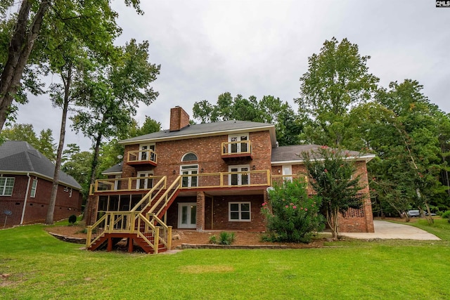 rear view of house with a patio area, a wooden deck, and a lawn