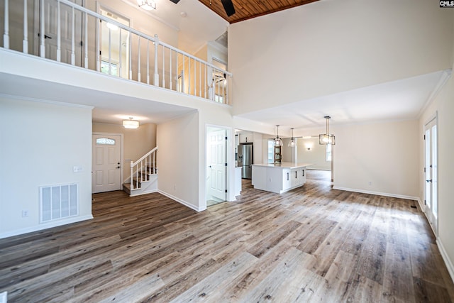 unfurnished living room with a high ceiling, a healthy amount of sunlight, hardwood / wood-style floors, and wooden ceiling