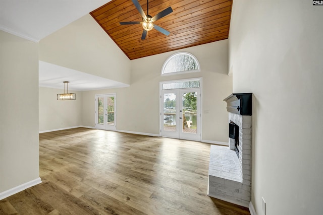 unfurnished living room featuring ceiling fan, wooden ceiling, a brick fireplace, and french doors