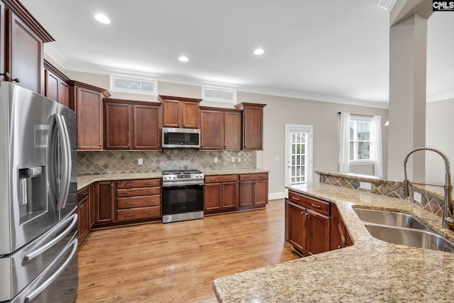 kitchen featuring sink, crown molding, light stone countertops, and appliances with stainless steel finishes