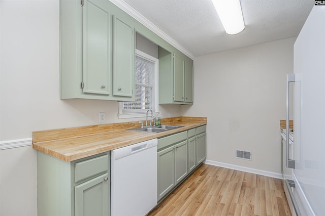 kitchen with butcher block counters, white dishwasher, a textured ceiling, green cabinetry, and sink