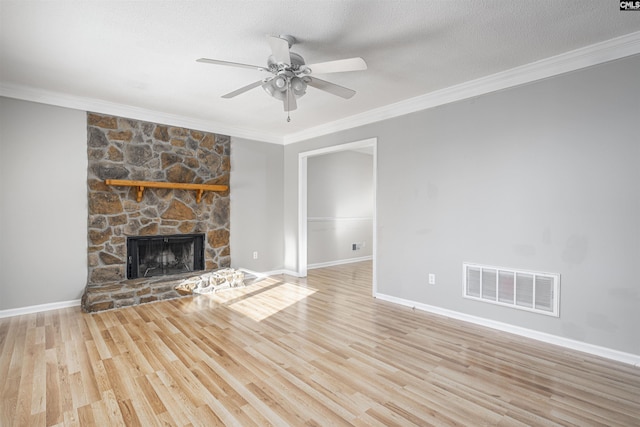 unfurnished living room featuring a textured ceiling, light hardwood / wood-style flooring, ornamental molding, and a stone fireplace