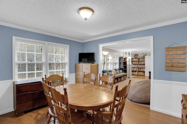 dining room with light wood-type flooring, a wealth of natural light, crown molding, and a textured ceiling