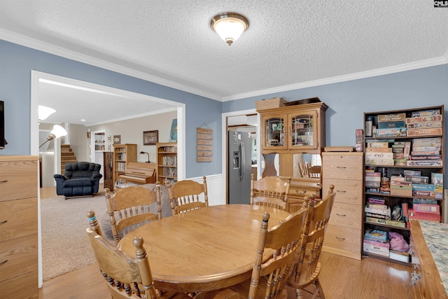 dining space featuring light hardwood / wood-style floors, a textured ceiling, and ornamental molding