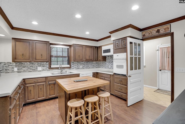 kitchen with oven, wooden counters, sink, light hardwood / wood-style flooring, and a breakfast bar area