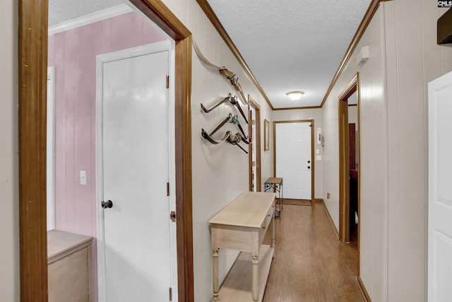 hall featuring a textured ceiling, light hardwood / wood-style flooring, and ornamental molding