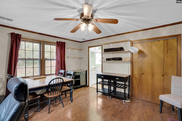 dining area featuring ornamental molding, a textured ceiling, and wood-type flooring