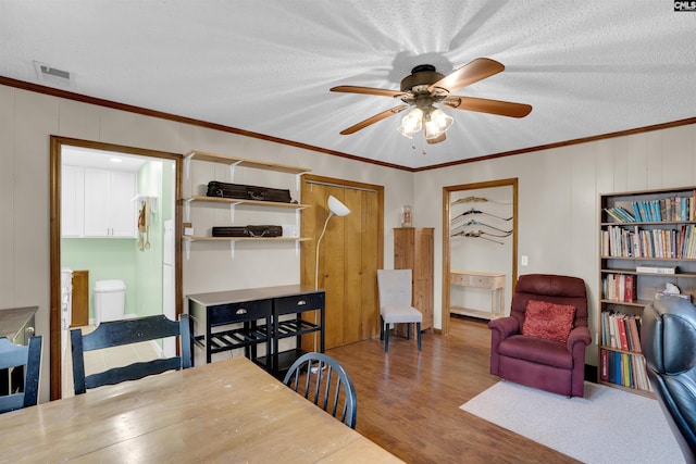 dining area featuring ceiling fan, ornamental molding, hardwood / wood-style floors, and a textured ceiling